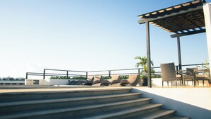 A rooftop terrace with a pergola, outdoor seating, and steps leading up to the terrace. - Torre Diez by Grupo Amber (Playa del Carmen)