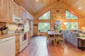 A cabin interior with wooden walls, a kitchen area, a dining table, and a seating area. - Elk House (Packwood)