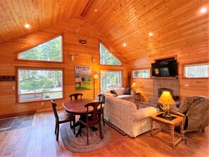 A cozy cabin interior with a dining table, sofa, and fireplace. - Elk House (Packwood)