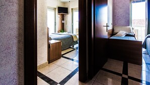 A hotel room with a bed, a bedside table, a TV, and a window. - Hotel Baviera (Chioggia)