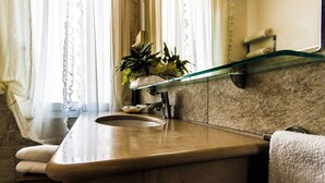 A bathroom with a marble sink, a glass shelf above the sink, and a towel rack. - Hotel Baviera (Chioggia)