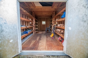 A wooden interior with shelves on both sides, a chair in the center, and a broom leaning against the right wall. - Little Woods Outpost (Randle)