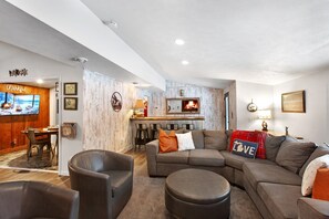 Ein gemütliches Wohnzimmer mit einer Eckcouch, einem Kamin und einem Fernseher.