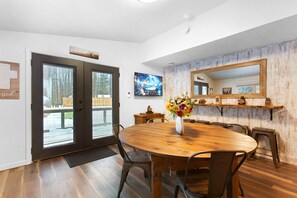 Ein Essbereich mit einem Holztisch und Stühlen, einer Blumenvase und einem großen Spiegel an der Wand.