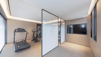 A modern room with a treadmill, stationary bike, and a flat-screen TV mounted on the wall.