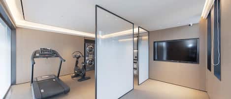 A modern room with a treadmill, stationary bike, and a flat-screen TV mounted on the wall.