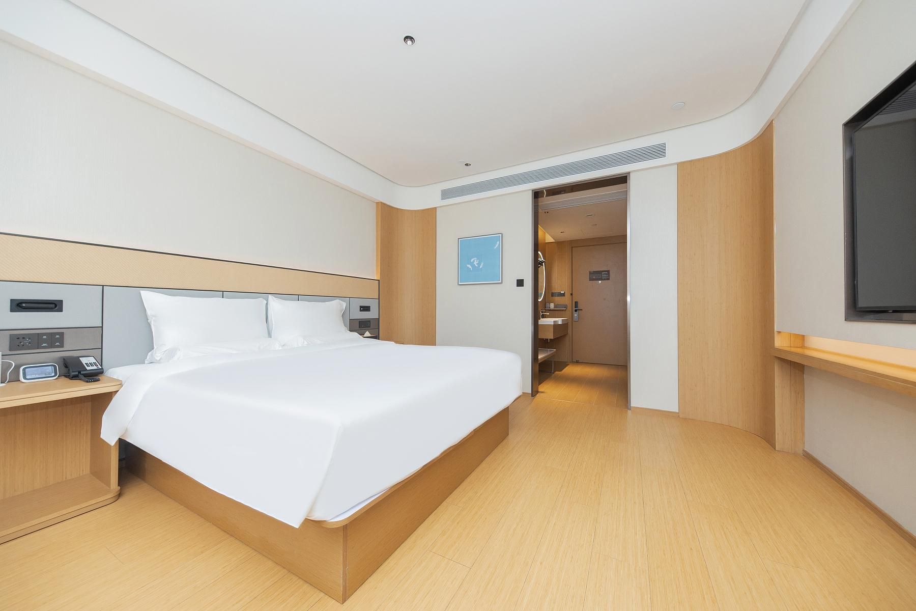 A hotel room with a bed, bedside table, and a television.