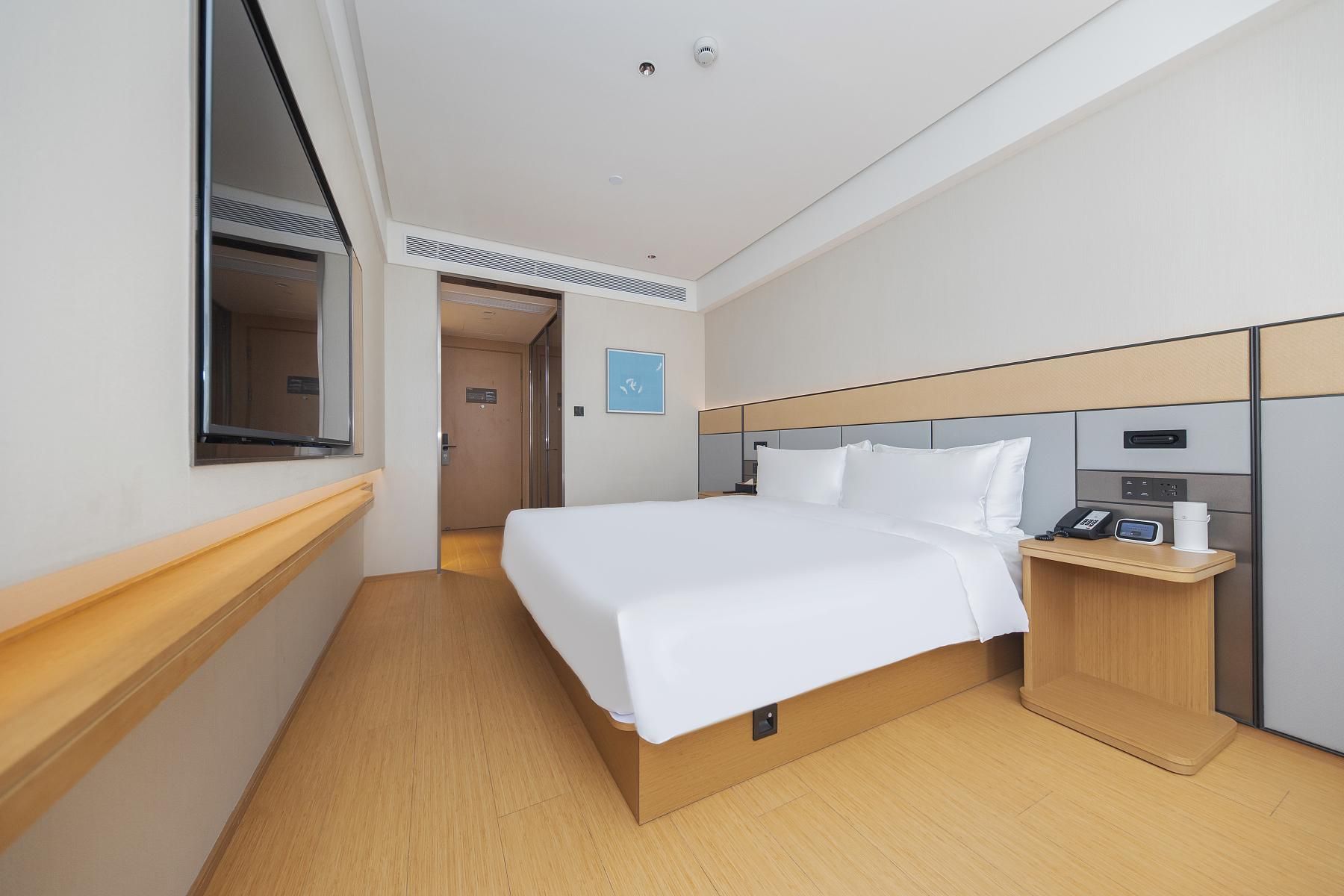 Una camera d'albergo con un letto, un comodino e una finestra.