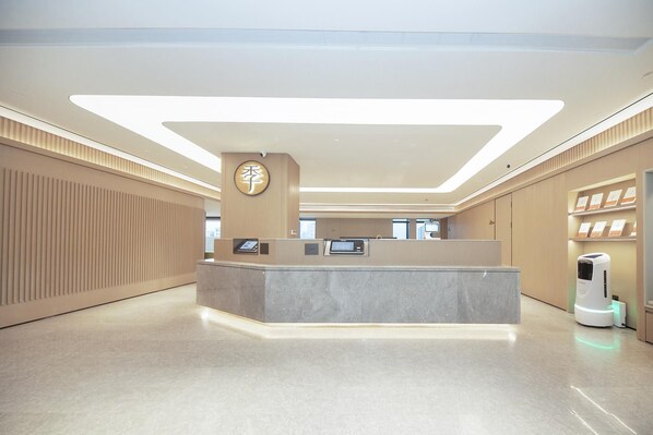A modern reception area with a marble counter, a clock, and a self-service kiosk.