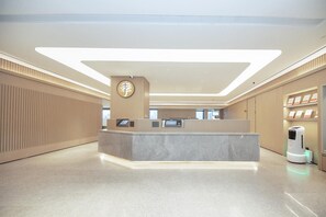 A modern reception area with a marble counter, a clock, and a self-service kiosk. - Ji Hotel (Hangzhou)