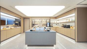 Una cucina moderna con isola centrale, elettrodomestici in acciaio inossidabile e una lampada a sospensione luminosa.