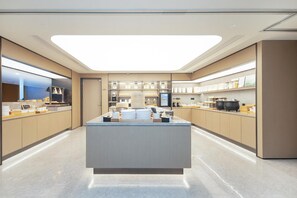 A modern kitchen with a central island, stainless steel appliances, and a bright overhead light. - Ji Hotel (Hangzhou)