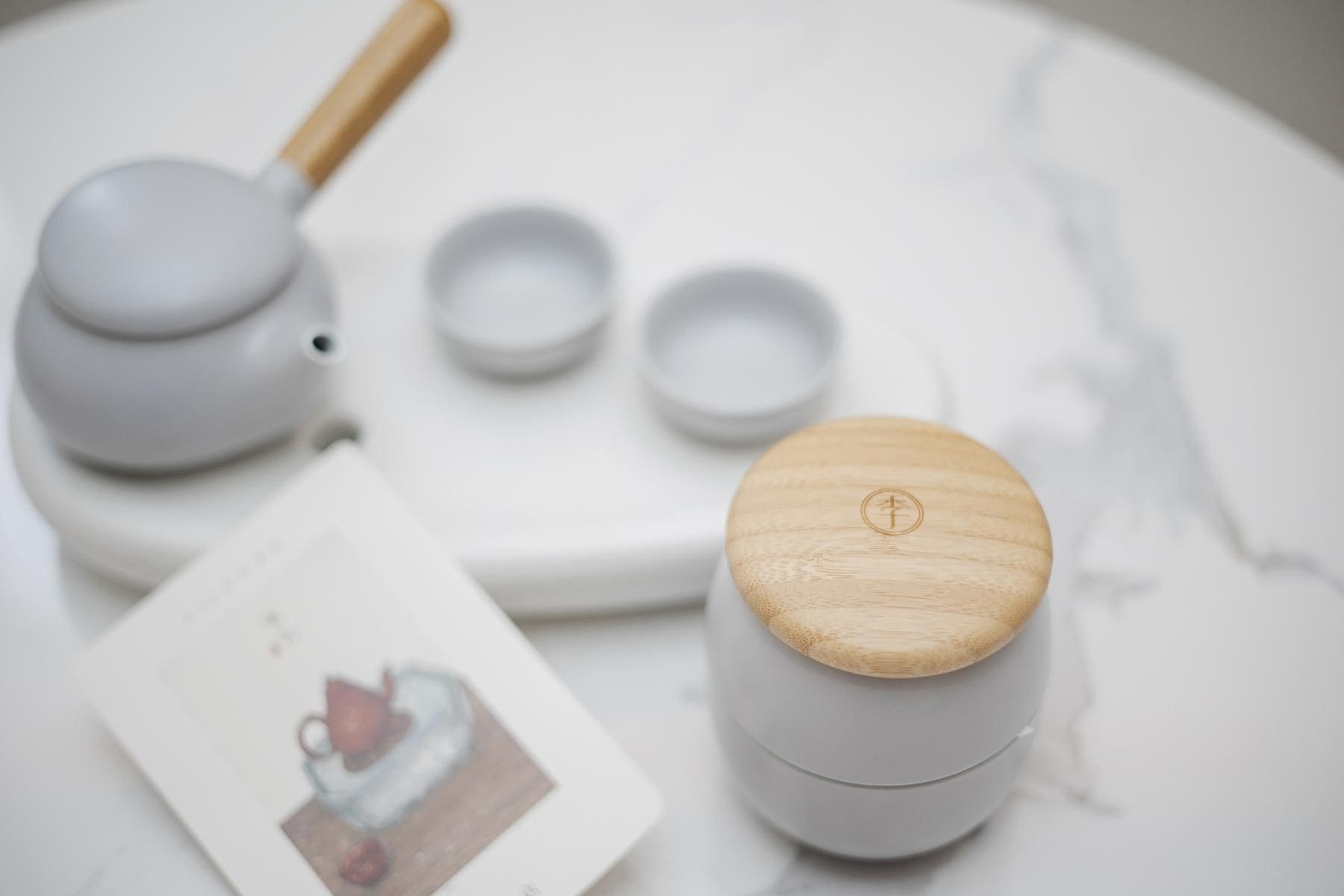 A set of white ceramic tea cups with wooden lids on a marble surface.