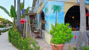 Ein Restaurant mit Außenbereich, einer Palme und einem Wandbild mit Strandmotiv.