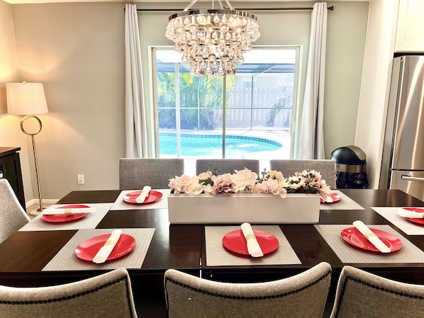 Comedor con vista a una piscina, un candelabro y una cocina moderna.