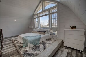 Ein Schlafzimmer mit Bett, Nachttisch, Lampe und Kommode.