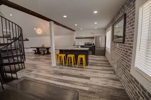 Eine moderne Küche mit einer zentralen Kochinsel, Barhocker und einer Treppe zu einer oberen Ebene.