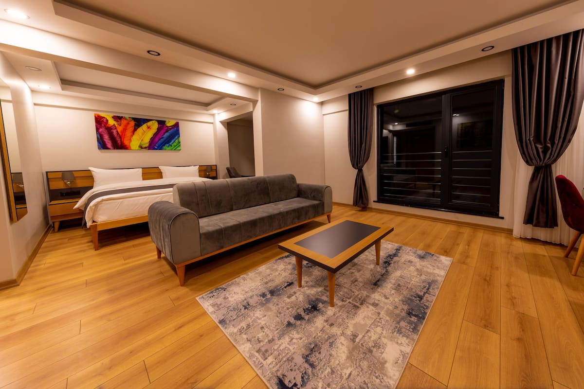 A modern hotel room with a bed, sofa, and a small table.