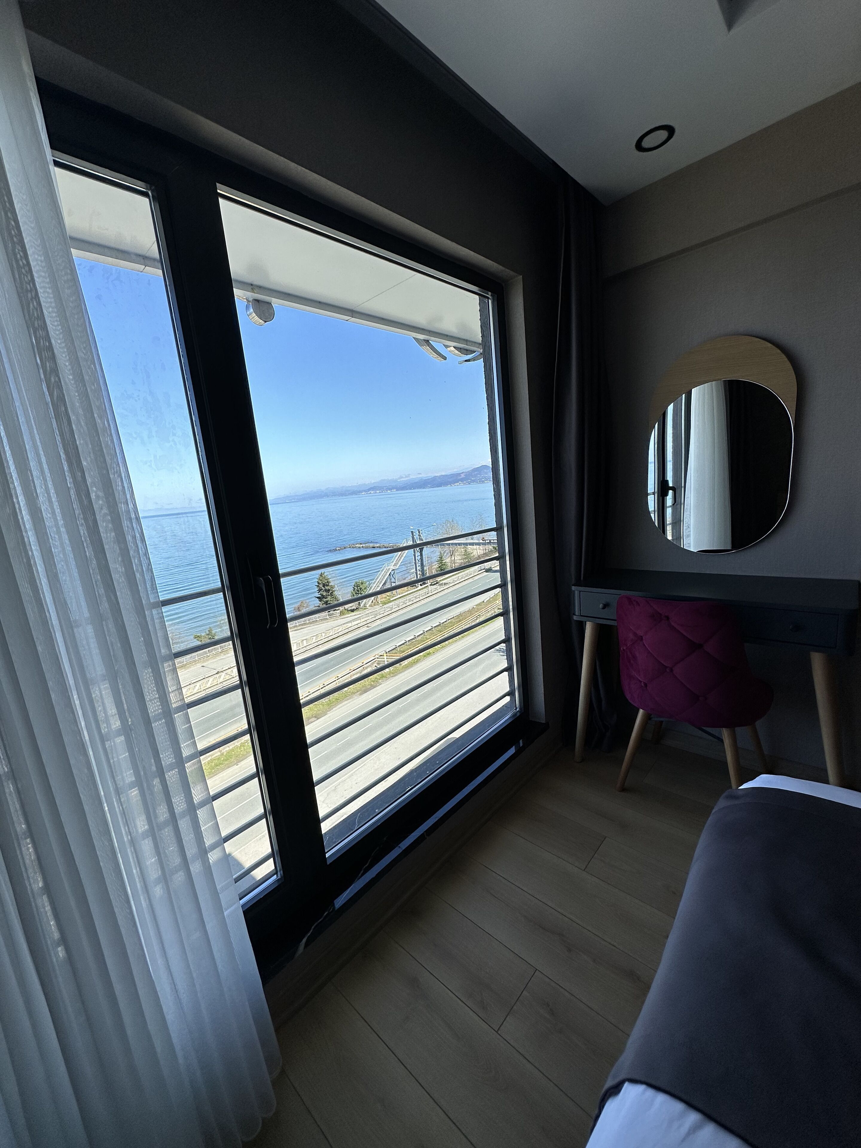 Een kamer met een grote schuifdeur die leidt naar een balkon met uitzicht op een waterpartij en een brug.