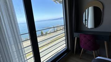 Een kamer met een grote schuifdeur die leidt naar een balkon met uitzicht op een waterpartij en een brug.