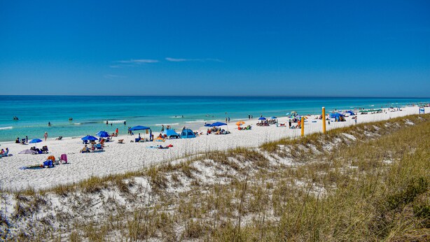 A beach with white sand, clear blue water, and people relaxing under umbrellas. - Private Beach Access~2 pools~tennis court~Balcony view~Short Walk to Beach (Destin)