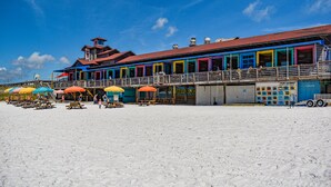 A beachside building with multiple colorful rooms and a covered seating area. - Private Beach Access~2 pools~tennis court~Balcony view~Short Walk to Beach (Destin)