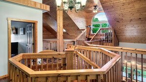 Un interior de madera con una escalera, una araña y vistas al exterior.