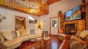 Una sala de estar acogedora con una escalera de madera, una chimenea y un televisor.