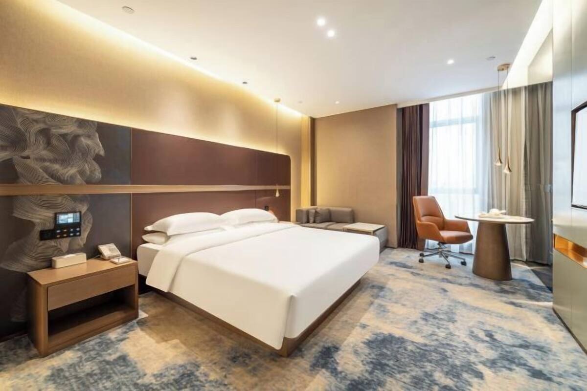 Une chambre d’hôtel moderne, dotée d’un grand lit, d’une table de chevet, d’une chaise et d’un bureau.