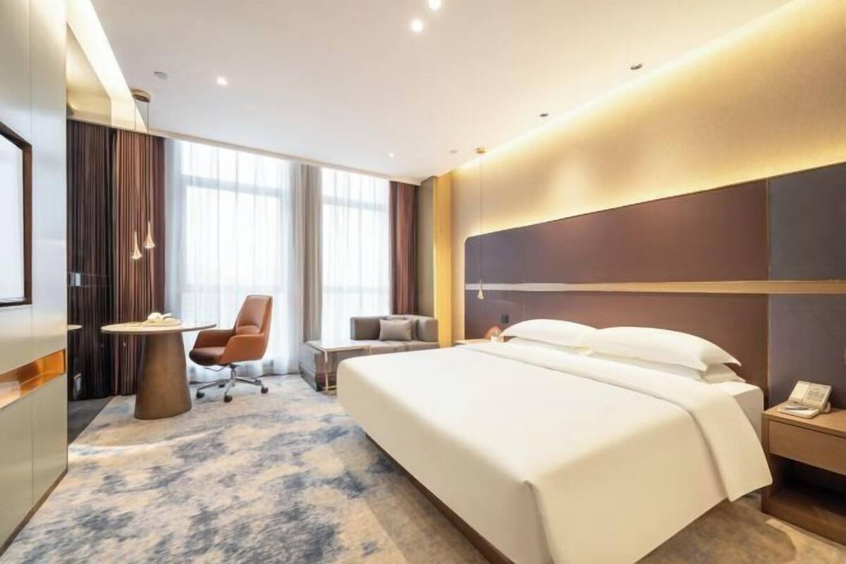 Une chambre d’hôtel avec un grand lit, un bureau, une chaise et un téléviseur.