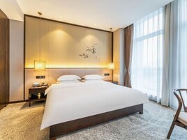Habitación de hotel con una cama grande, lámparas de noche, mesita de noche y vistas al exterior por la ventana.