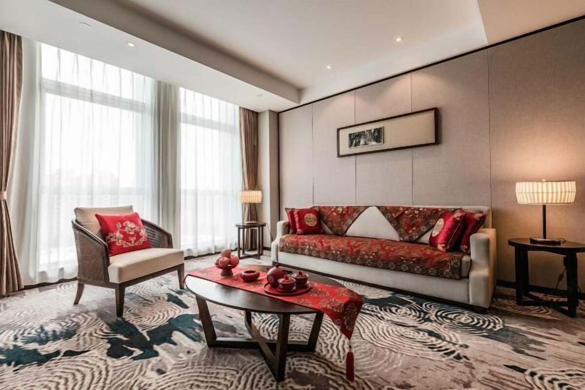 Ein modernes Hotelzimmer mit Sofa, Sesseln und einem Couchtisch mit Teekannen.