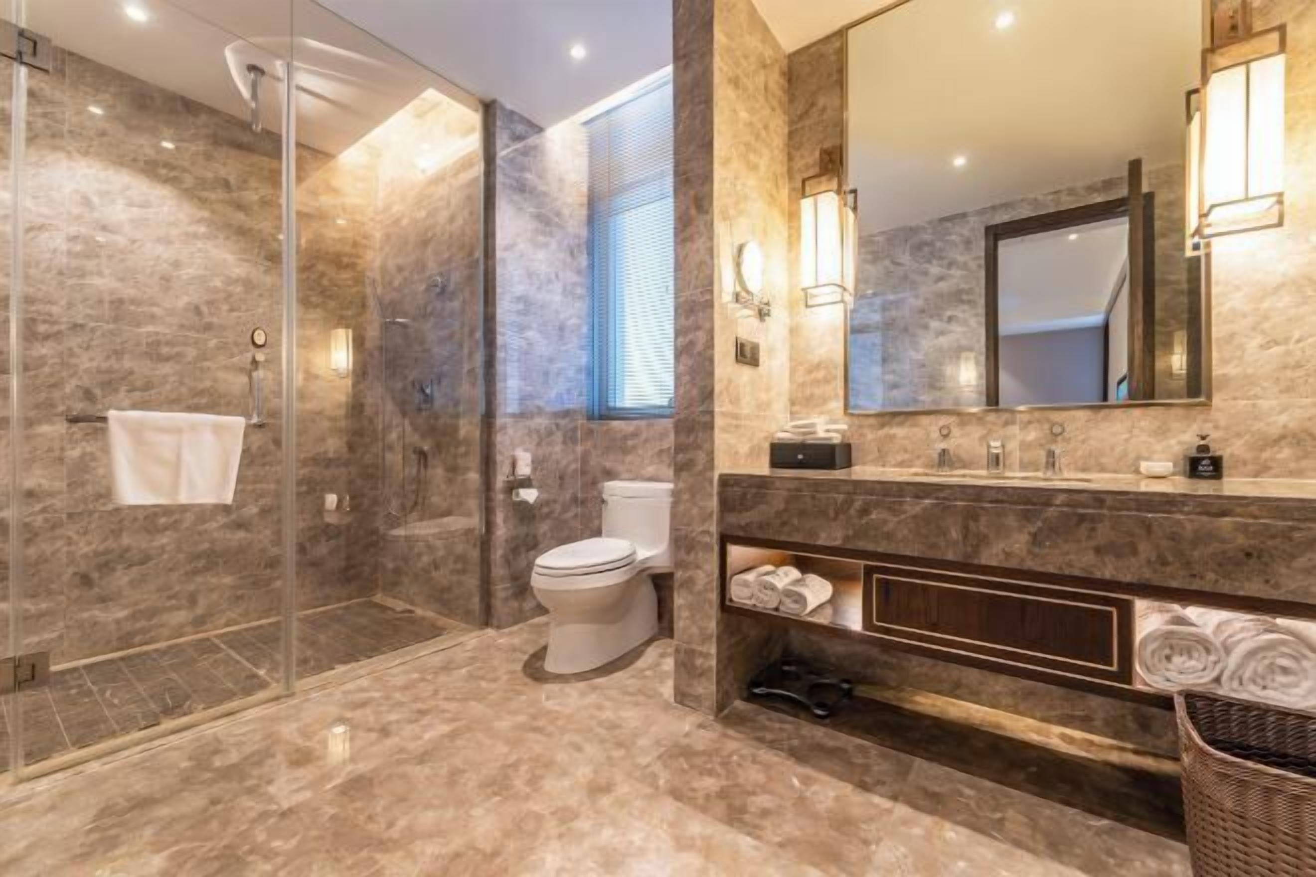 A modern bathroom with a glass-enclosed shower, a toilet, a vanity with a mirror, and a towel rack.