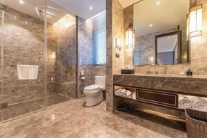 Ein modernes Badezimmer mit einer Duschkabine, einer Toilette, einem Waschtisch mit Spiegel und einem Handtuchhalter.