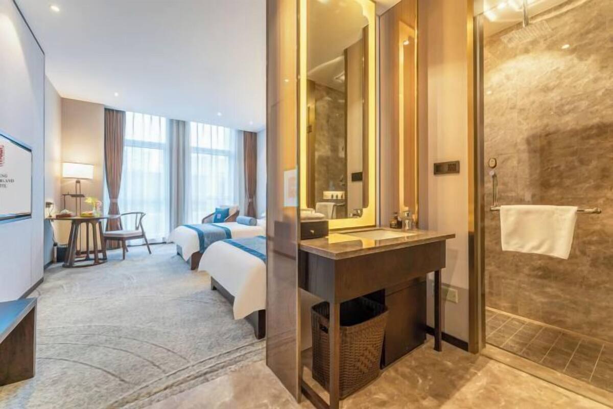 Une chambre d’hôtel équipée d’un lit, d’un bureau, d’un miroir, d’une douche et d’un meuble-lavabo.