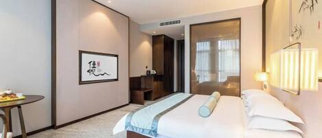 A hotel room with a bed, bedside table, lamp, and artwork on the wall.