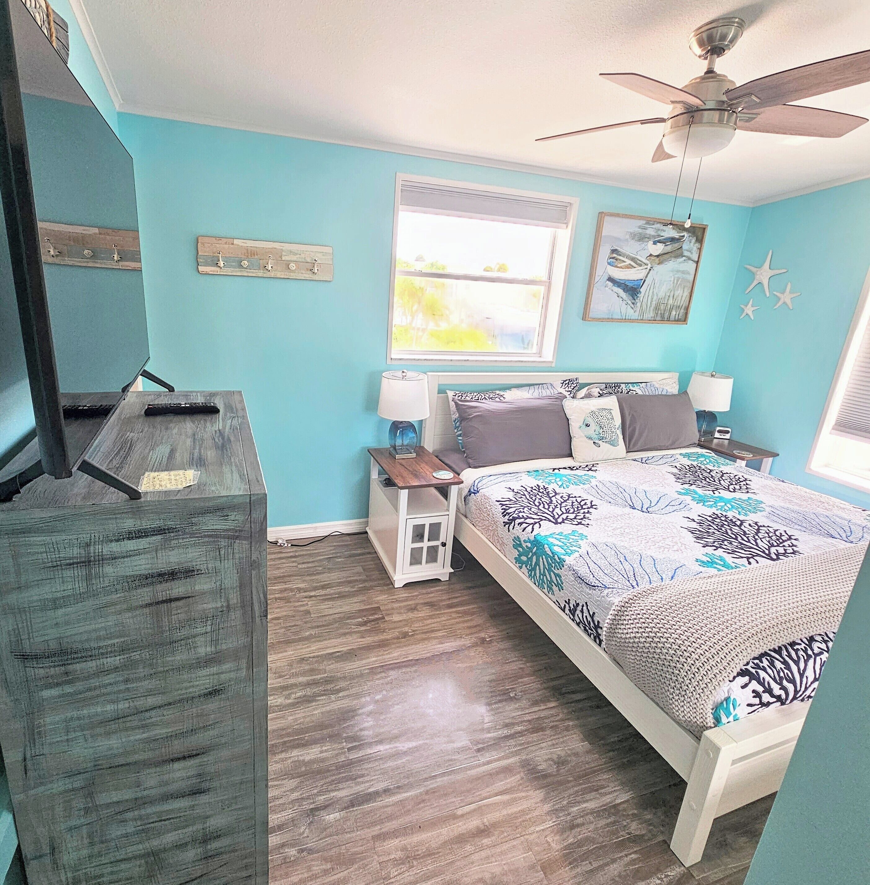 A bedroom with a bed, a desk, a chair, a window, and a ceiling fan.