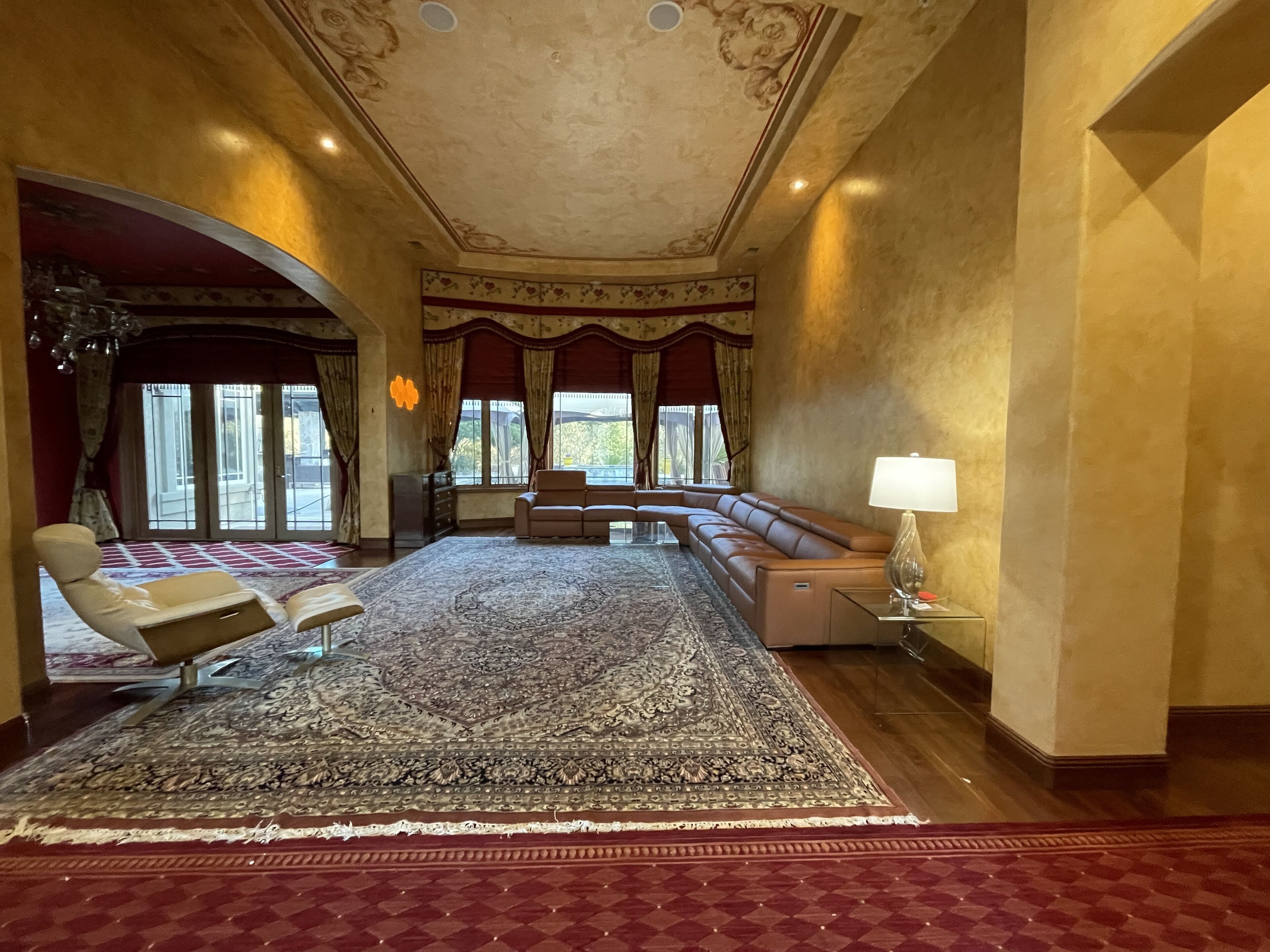 Ein geräumiges Wohnzimmer mit einem großen, gemusterten Teppich, einem Ledersofa und einer Liege.