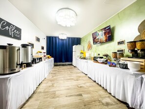A buffet setup with coffee and cereal dispensers, a television screen, and a sign reading "Good Morning!". - Neptune Oceanfront Rentals (Hollywood)
