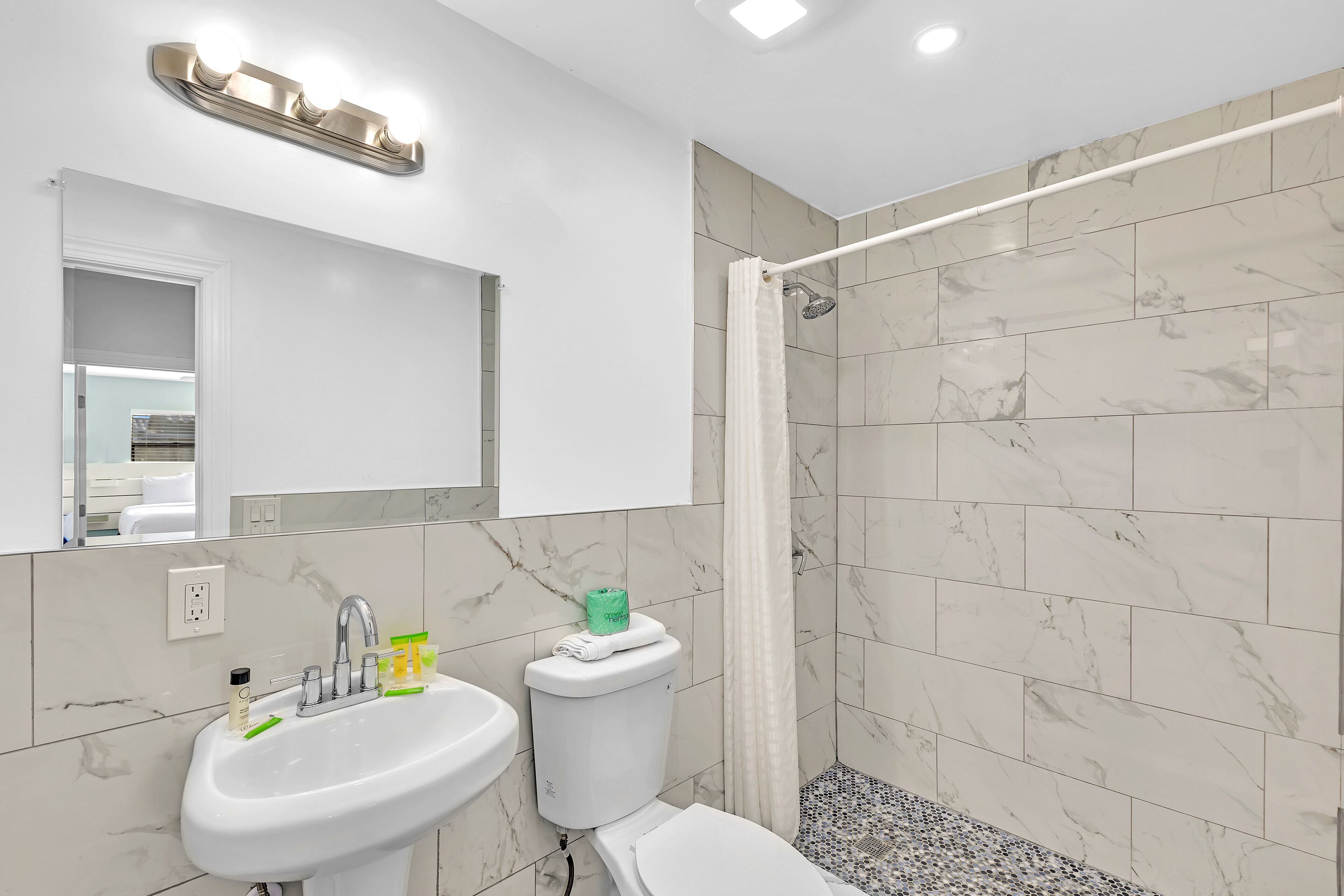 A modern bathroom with a sink, mirror, and shower.