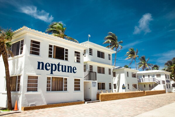 A white building with the word "neptune" on the side, multiple windows, and a balcony. - Neptune Oceanfront Rentals (Hollywood)