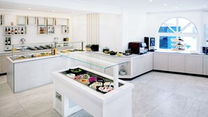 Un vestíbul d'hotel modern amb una zona de buffet central, una recepció i un gran finestral amb vistes.