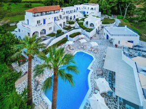 A resort with a swimming pool, palm trees, and a white building with blue accents. - Theo Bungalows Kriopigi (Kassandra)