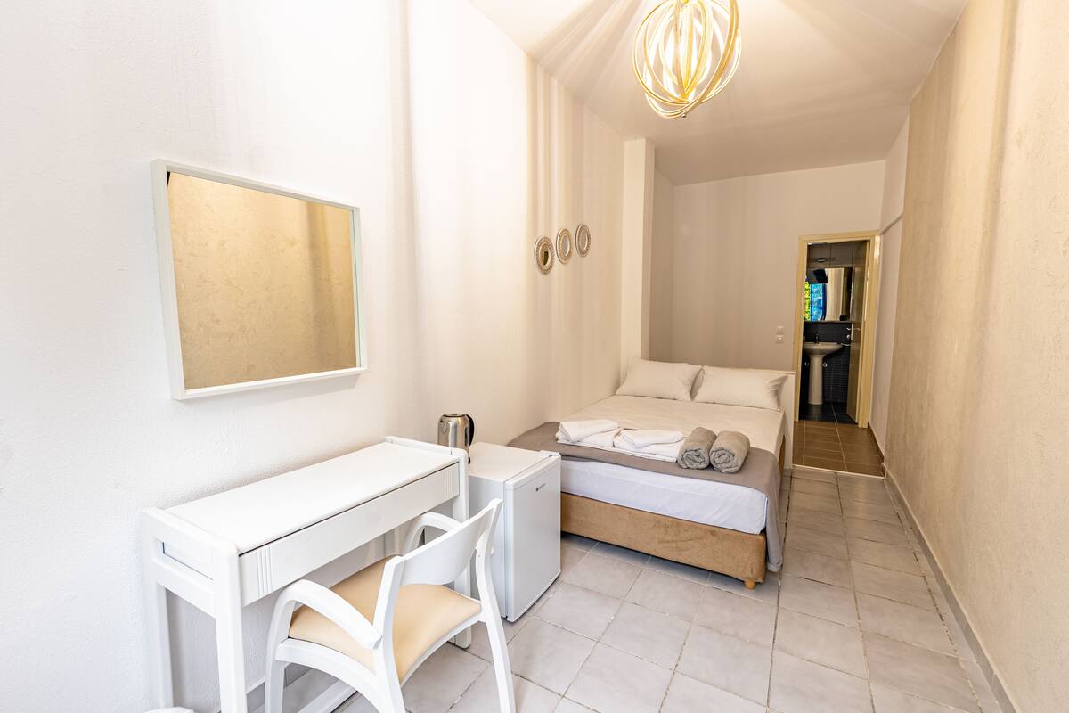 Een kleine hotelkamer met een bed, een bureau en een stoel.