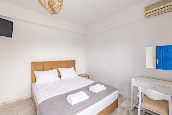 A neatly arranged hotel room with a bed, bedside table, and a desk with a chair. - Theo Bungalows Kriopigi (Kassandra)
