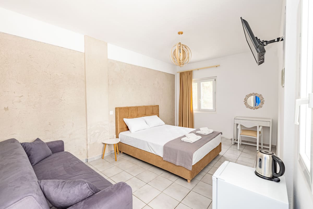 Een moderne hotelkamer met een bed, een bank, een tafeltje en een waterkoker.