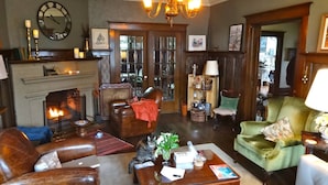 Ein gemütliches Wohnzimmer mit Kamin, Ledersesseln, einem Couchtisch und einer Chandelüster.