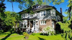 Ein zweistöckiges Haus mit Veranda, Ziegelaußenwand und mehreren Fenstern.