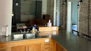 Une cuisine moderne dotée d’un plan de travail en bois, d’un évier en acier inoxydable et d’un luminaire suspendu.