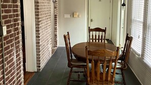 Un coin repas avec un mur en briques, un ventilateur de plafond et une table à manger entourée de chaises en bois.